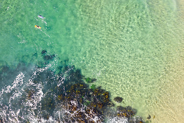 Image showing Surfers paddle out for waves at a beach in summer