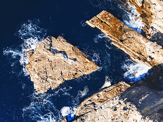 Image showing Shapely exposed rock slabs in deep water off the coast