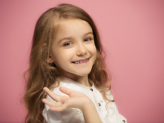 Image showing The happy teen girl standing and smiling against pink background.