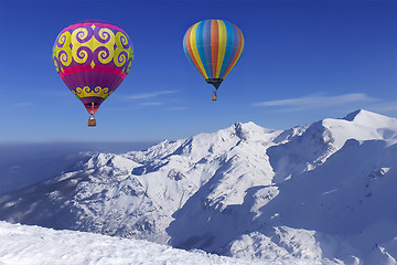 Image showing Colorful balloons flying over snow-covered mountains