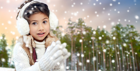 Image showing little girl wearing earmuffs over winter forest