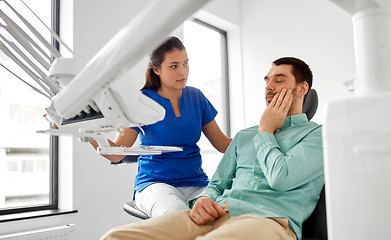 Image showing man with toothache and dentist at dental clinic