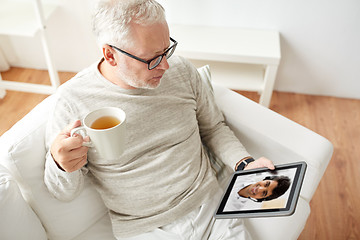 Image showing senior man having video call on tablet pc at home