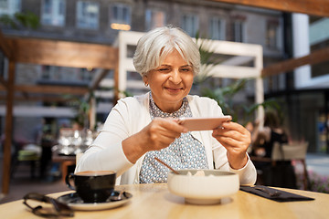 Image showing senior woman photographing food at street cafe