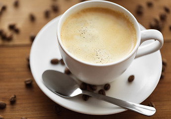 Image showing close up coffee cup and beans on wooden table