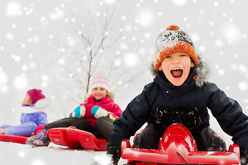 Image showing happy kids sliding on sleds in winter