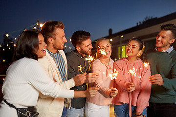 Image showing happy friends with sparklers at rooftop party