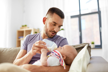 Image showing father feeding baby daughter from bottle at home