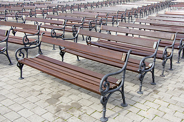 Image showing Lot of Rows of empty brown wooden benches 