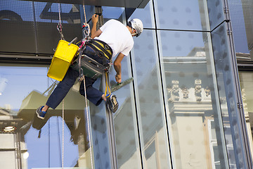 Image showing Window washer cleaning the windows of shopping center