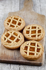 Image showing Fresh baked tarts with marmalade or apricot jam filling on cutti