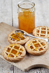 Image showing Fresh baked tarts with marmalade filling and apricot jam in glas