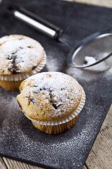 Image showing Two fresh homemade muffins with sugar powder and metal strainer 