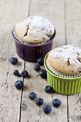 Image showing Two homemade fresh muffins on ceramic green and purple bowls wit