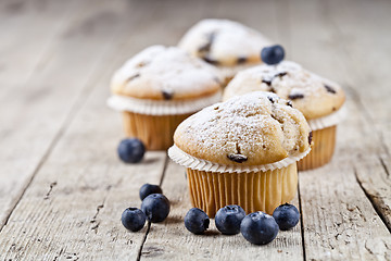 Image showing Four fresh homemade muffins with blueberries on rustic wooden ta