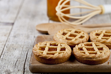 Image showing Fresh baked tarts with marmalade or apricot jam filling and on c