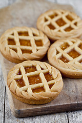 Image showing Fresh baked tarts with marmalade or apricot jam filling on cutti