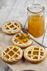 Image showing Fresh baked tarts with marmalade filling and apricot jam in glas