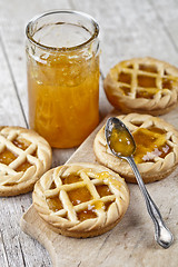 Image showing Fresh baked tarts with marmalade filling and apricot jam in glas