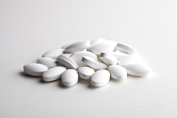 Image showing Pile of white drug pills laying on white background. Medical con