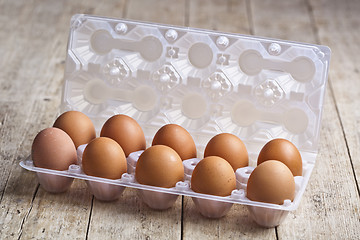 Image showing Fresh chicken eggs on plastic container on rustic wooden table.