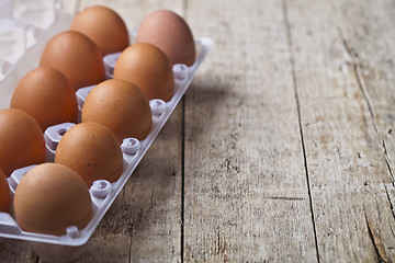 Image showing Fresh chicken eggs on plastic container on rustic wooden table b