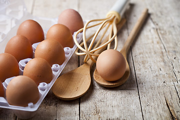 Image showing Fresh chicken eggs on plastic container and kitchen utensil on r