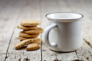 Image showing Cup of milk and stack of fresh baked oat cookies on rustic woode