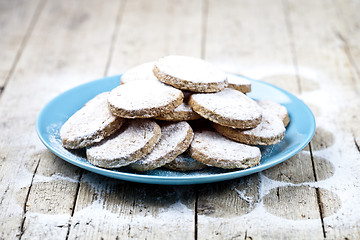 Image showing Fresh baked oat cookies with sugar powderon blue ceramic plate o