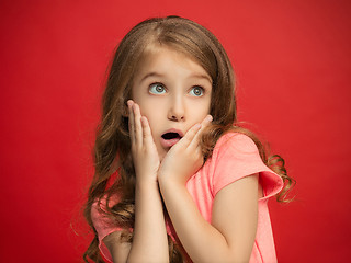 Image showing Beautiful teen girl looking suprised isolated on red