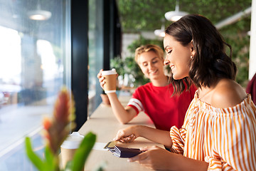 Image showing female friends paying by credit card at cafe