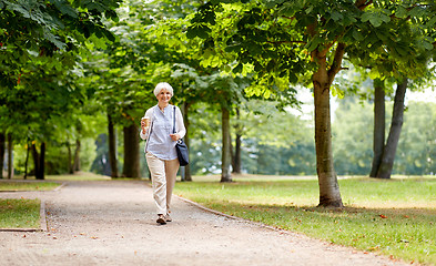 Image showing senior woman walking with takeaway coffee at park