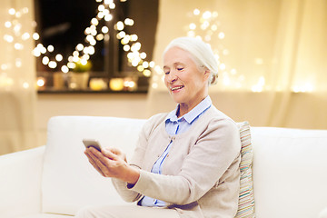 Image showing senior woman with smartphone at home on christmas