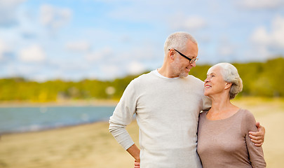 Image showing happy senior couple hugging over beach background