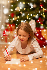 Image showing smiling girl writing christmas wish list at home