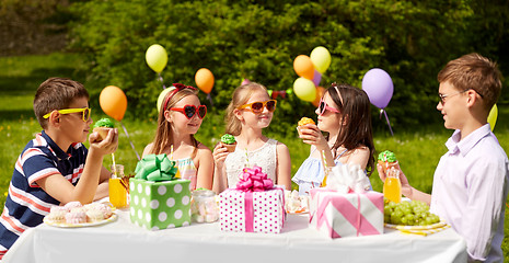 Image showing kids eating cupcakes on birthday party in summer