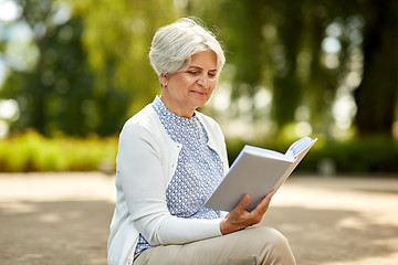 Image showing senior woman reading book at summer park