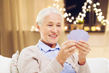 Image showing happy senior woman playing cards on christmas