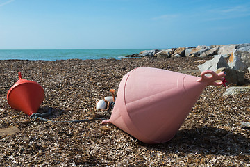 Image showing Two big buoys on the beach, azure sea and the rocky beach