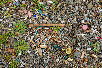 Image showing Garbage on the beach near the big city. Used dirty plastic sticks and other garbage. Environmental pollution.