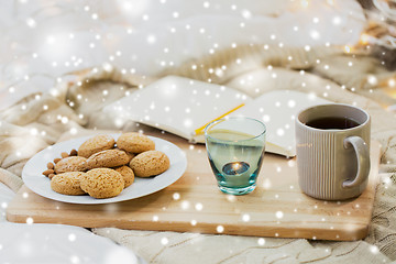 Image showing cookies, tea and candle at home over snow