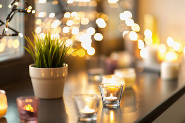 Image showing candles burning on window sill with garland lights