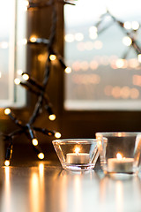 Image showing candles burning on window sill with garland lights