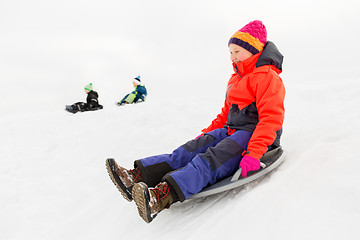 Image showing happy kids sliding on sled down hill in winter