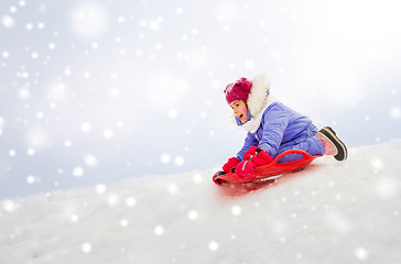 Image showing girl sliding down on snow saucer sled in winter