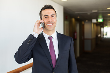 Image showing smiling businessman calling on smartphone at hotel