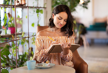 Image showing happy woman with notebook at coffee shop or cafe