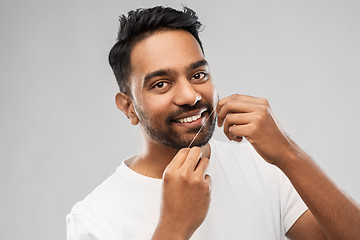 Image showing indian man with dental floss cleaning teeth