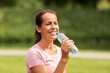 Image showing woman drinking water after exercising in park