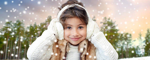 Image showing little girl wearing earmuffs over winter forest